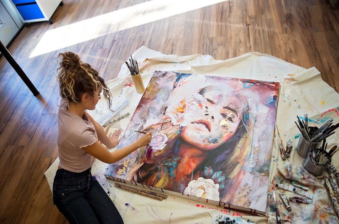 Damitra painting a portrait on the floor in well lit room