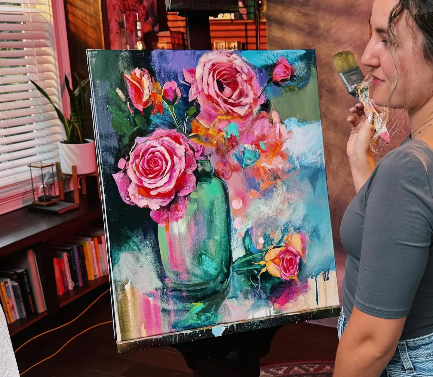 Girl standing in front of painting on easel with bold colored flowers painted in a vase